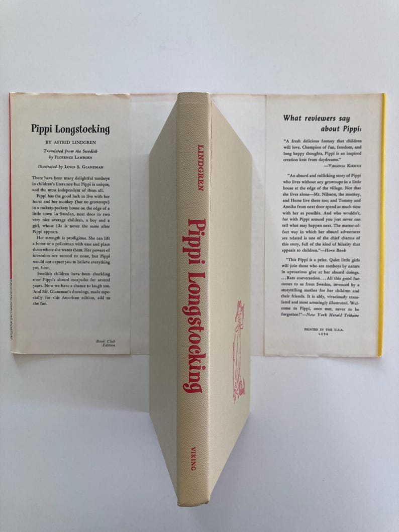 May include: A hardcover book titled Pippi Longstocking by Astrid Lindgren with a beige dust jacket. The spine features red text and a small illustration. The front and back flaps contain printed summaries and reviews of the children's story.