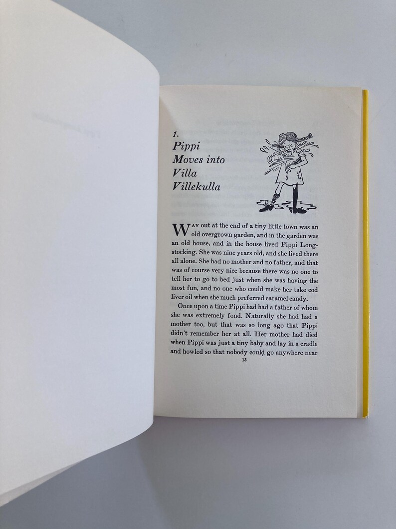 May include: An open book page featuring the chapter title 1. Pippi Moves into Villa Villekulla with a black and white line drawing of a girl with braided hair. The text begins with Way out at the end of a tiny little town was an old overgrown garden.