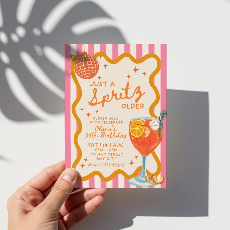 Op de afbeelding: Een verjaardagsuitnodiging met een roze en witte gestreepte achtergrond en oranje accenten. De tekst luidt "Just a Spritz Older" met details voor Olivia's 30e verjaardag. Een discobal en een cocktailillustratie zijn ook te zien.