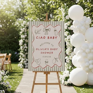 May include: A baby shower sign on a wooden easel. The sign reads "Ciao Baby, Welcome to Olivia's Baby Shower 17.02.26" with illustrations of a bow, baby bottle, onesie, pacifier, and lemon. The background has a striped pattern.