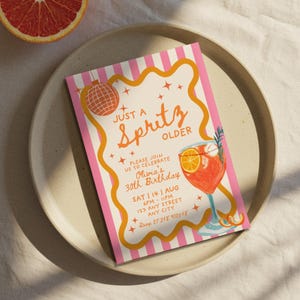 Op de afbeelding: Een roze en wit gestreepte uitnodiging met de tekst "Just a Spritz Older" in oranje script. De uitnodiging bevat details voor Olivia's 30e verjaardag, met een cocktailillustratie en een discobal-afbeelding.