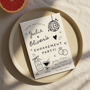 Könnte beinhalten: Cremefarbene Einladungskarte zur Verlobungsfeier mit schwarzen Illustrationen, darunter eine Discokugel, Ringe und Champagner. Der Text lautet "Julia & Oliver's Engagement Party!". Auf einem beigen Teller mit einer Grapefruitscheibe.
