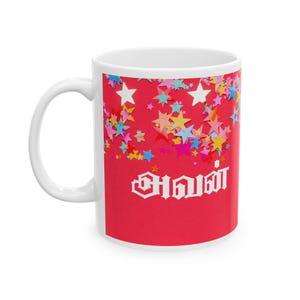 Puede incluir: Taza de cerámica blanca con fondo rojo y confeti de estrellas de colores. El texto "அவள்" está impreso en blanco en la taza.