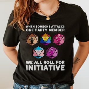 May include: Black t-shirt with a white graphic of dice with different symbols. The text "When someone attacks one party member we all roll for initiative" is printed on the shirt.