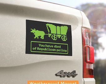 May include: A black and green weatherproof magnet with a pixelated image of a covered wagon pulled by an ox. The text "You have died of Republican policy" is written below the image.