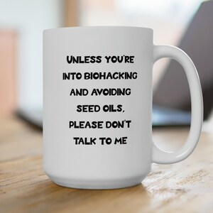 May include: White ceramic coffee mug with black text that reads "Unless you're into biohacking and avoiding seed oils, please don't talk to me."