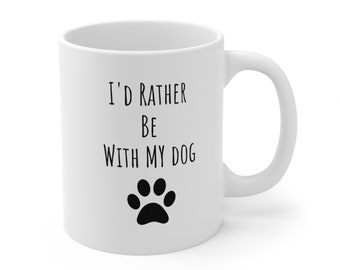 May include: White ceramic mug with the text "I'd rather be with my dog" in black, along with a black paw print. The mug has a curved handle and a glossy finish. A perfect gift for dog lovers.