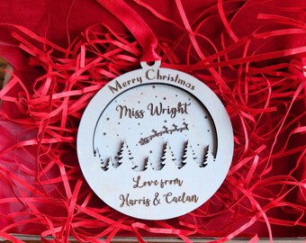 Puede incluir: Un adorno navideño de madera blanco con una escena nevada y el texto "Merry Christmas Miss Wright Love from Harris & Caelan".