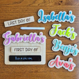 May include: Wooden school sign with the text "LAST DAY OF" and "FIRST DAY OF Reception". Includes name cutouts for Isabella's, Jack's, Benji's, Ava's, and Gabriella's. A white marker is also included.