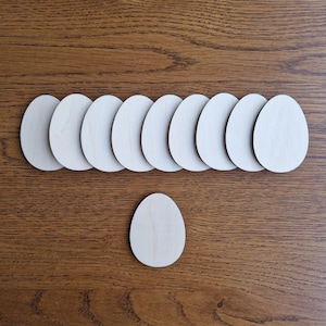 May include: A set of ten unfinished wooden egg shapes, ideal for crafting and decorating. The eggs are arranged in a row, with one egg placed below the row.