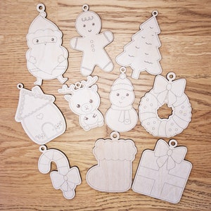May include: Set of ten unfinished wooden Christmas decorations. The decorations feature various festive themes, including a gingerbread person, a Christmas tree, a snowman, a reindeer, a candy cane, a stocking, a gift box, a house, Santa Claus, and a wreath.