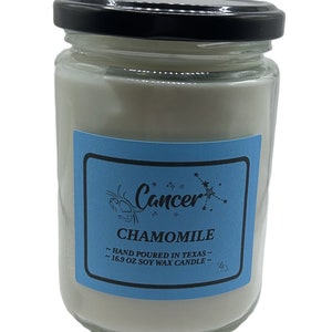 Könnte beinhalten: Eine Glas-Kerze in einem Einmachglas mit einem blauen Etikett, auf dem "Cancer" und "Chamomile" steht. Das Etikett trägt außerdem die Aufschrift "Hand Poured in Texas" und "16.9 oz Soy Wax Candle".