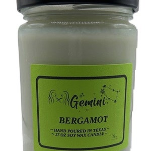 Könnte beinhalten: Ein grünes und weißes Kerzengefäß mit schwarzem Deckel. Das Etikett lautet "Gemini: Bergamotte - Handgefertigt in Texas - 17 oz Sojawachskerze".