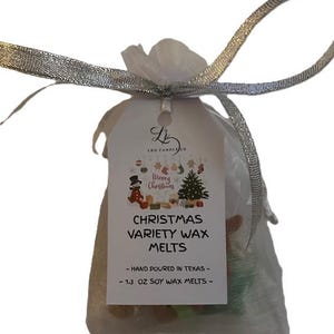 Könnte beinhalten: Eine transparente Organzatasche, gebunden mit einem silbernen Band, mit weihnachtlichen Wachsschmelzen. Ein weißes Etikett trägt die Aufschrift "Merry Christmas" und "Christmas Variety Wax Melts". Die Tasche enthält 37 Gramm Sojawachs-Schmelze.