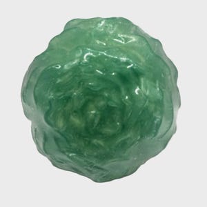 Könnte beinhalten: Ein grünes, durchsichtiges, rundes Dekorationsobjekt mit einer strukturierten Oberfläche. Das Objekt ähnelt einer Rosenknospe.