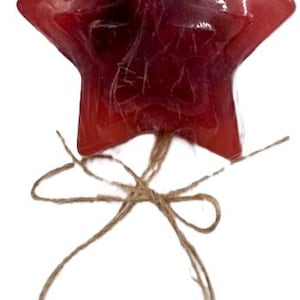 Könnte beinhalten: Eine rote sternförmige Seife mit einer Schnur aus Bindfaden. Die Seife ist durchscheinend und hat ein Wirbelmuster.