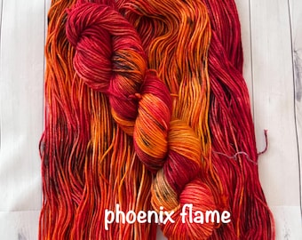 May include: A skein of yarn in shades of red, orange, and yellow with black speckles. The yarn is called "phoenix flame".