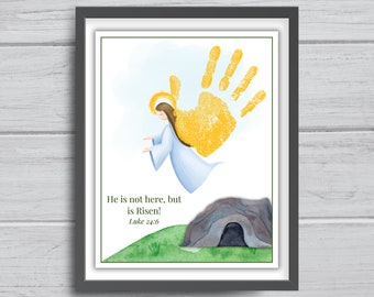 May include: A framed print featuring a watercolor illustration of an angel with a golden halo and a large yellow handprint. The text "He is not here, but is Risen! Luke 24:6" is displayed below the angel and handprint, above a tomb.