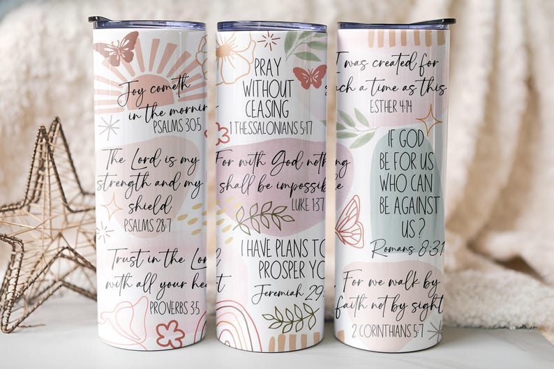 Puede incluir: Tres vasos aislados blancos con citas inspiradoras y dise&ntilde;os florales y de mariposas. Los vasos presentan citas de Salmos, Proverbios y otros vers&iacute;culos b&iacute;blicos en una paleta de colores pastel.