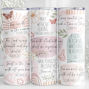 Puede incluir: Tres vasos aislados blancos con citas inspiradoras y dise&ntilde;os florales y de mariposas. Los vasos presentan textos de la Biblia en una paleta de colores pastel. Los vasos est&aacute;n decorados con mariposas, flores y rayos de sol.