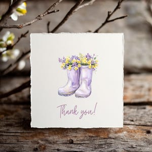 May include: A thank you card with a watercolor illustration of purple rain boots filled with yellow and purple flowers. The text "Thank you!" is written in purple below the boots.