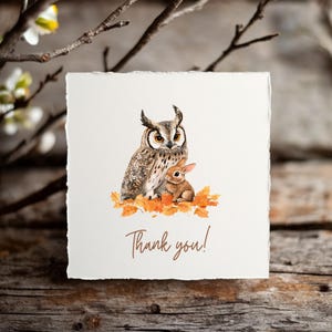 May include: A square card with a watercolor illustration of an owl and a rabbit sitting on autumn leaves. The text "Thank you!" is written in a brown script font. The card has a textured, off-white appearance.