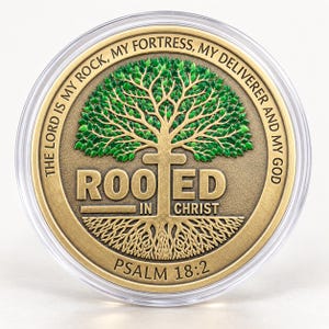 May include: A round gold-toned metal coin encased in a clear plastic protective shell. The coin features a green tree with visible roots and the text "ROOTED IN CHRIST" and "THE LORD IS MY ROCK, MY FORTRESS, MY DELIVERER AND MY GOD PSALM 18:2".