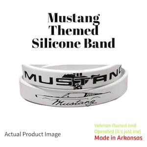 May include: White silicone band with "MUSTANG" in black lettering and a car silhouette. The band also features the word "Mustang" in a script font. The text "Mustang Themed Silicone Band" is at the top.