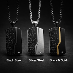 May include: Three steel dog tag pendants on chains. The tags are black, silver, and black with gold accents. Each tag has a textured pattern and a small, clear gem. The words "Black Steel", "Silver Steel", and "Black & Gold" are below the pendants.