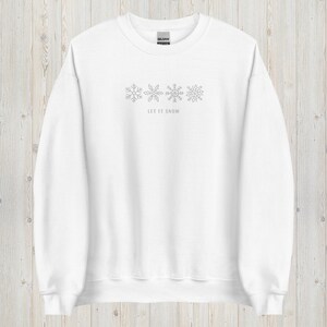 May include: White sweatshirt with a gray snowflake design and the text "Let it snow" on the front.