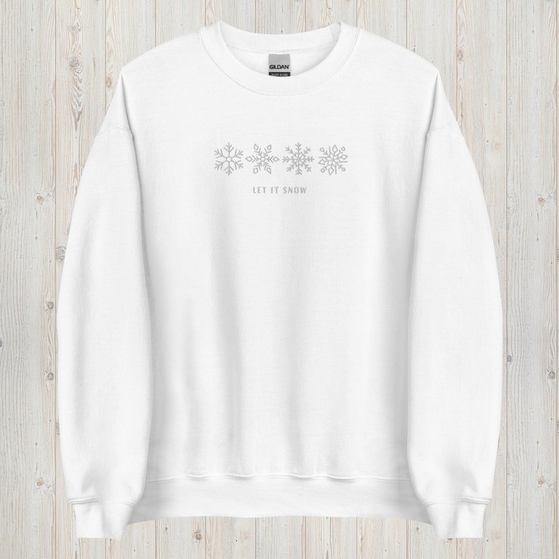 May include: White sweatshirt with a gray snowflake design and the text "Let it snow" on the front.