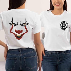 May include: Two white t-shirts, one with a graphic of Pennywise the clown's face and the other with the text "You'll Float Too" in a balloon shape.