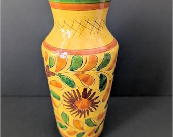Könnte beinhalten: Eine gelbe Keramikvase mit einem grünen, orangefarbenen und braunen Blumendesign. Die Vase hat einen schmalen Hals und einen breiten Boden.