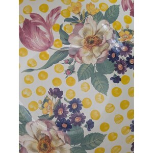 May include: A white surface with a floral pattern featuring pink tulips, cream-colored roses, and purple daisies. Yellow polka dots are scattered across the background, creating a vintage aesthetic.