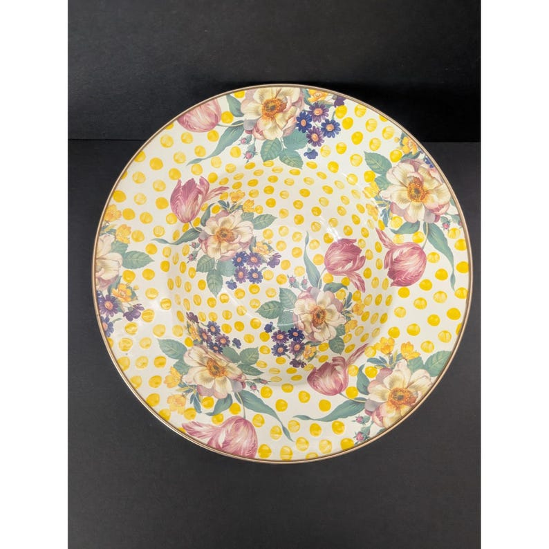 May include: A round, decorative serving bowl with a floral design. The bowl features a yellow polka dot background with a floral pattern of pink tulips, cream-colored flowers, and blue accents. The rim has a gold trim.