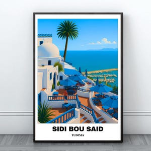 May include: A framed art print of Sidi Bou Said, Tunisia. The image depicts white buildings with blue accents, blue umbrellas, and a palm tree against a blue sky and sea. The text "SIDI BOU SAID TUNISIA" is at the bottom.