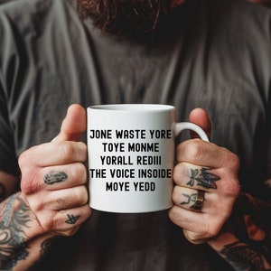 May include: White ceramic mug with black text that reads "Jone waste yore toye monme yorall redIII the voice insoide moye yedd".