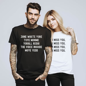May include: Two people wearing black and white t-shirts with text printed on them. The black t-shirt has the text "JONE WASTE YORE TOYE MONME YORALL REDIII THE VOICE INSOIDE MOYE YEDD". The white t-shirt has the text "I MISS YOU, I MISS YOU, I MISS YOU, I MISS YOU."