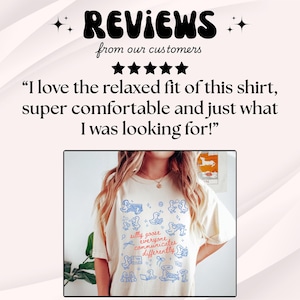 May include: Cream-colored t-shirt with a blue and white illustration of geese and the text "silly goose everyone communicates differently." The shirt also features a customer review.
