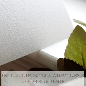 Pode incluir: Close-up de um papel branco texturizado com o texto "PRINTED ON HAHNEMUHLE WILLIAM TURNER COLD-PRESSED PAPER" impresso nele.