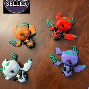 May include: Four Halloween-themed turtle figurines with spider accents. The turtles are painted in orange, red, purple, and white.
