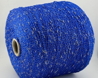 May include: A spool of blue yarn with silver glitter woven throughout. The yarn is wound tightly on a cardboard spool.