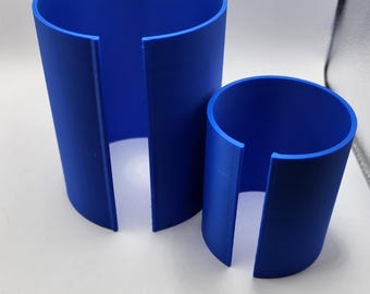 May include: Two blue plastic cylindrical containers with a split on one side. The containers are different sizes.