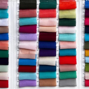 May include: A comprehensive fabric colour swatch chart featuring a grid of numerous small, rectangular textile samples in a wide variety of solid colours, including shades of red, blue, green, yellow, pink, purple, black, white, and neutral tones.