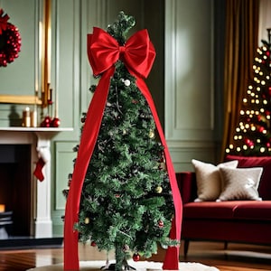 Puede incluir: Un árbol de Navidad decorado con un gran lazo rojo en la parte superior y una larga cinta roja que cae por el frente. El árbol está adornado con adornos y luces. El fondo incluye una chimenea, un sofá rojo y una corona navideña.