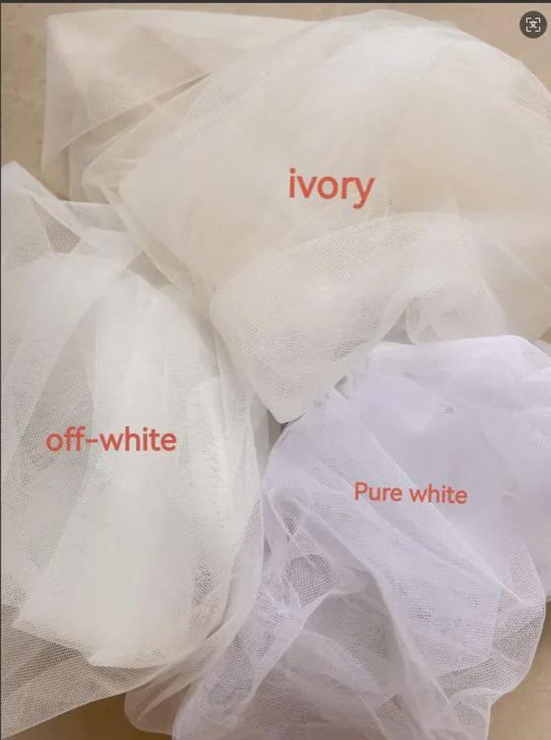 May include: Three swatches of sheer, fine-mesh tulle fabric arranged in overlapping layers. The fabric colors are labeled with text as ivory, off-white, and pure white, showcasing the distinct tonal differences between these three shades of white.