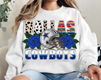 May include: White sweatshirt with a Dallas Cowboys graphic. The graphic features a football helmet, blue roses, and the text "Dallas Cowboys".