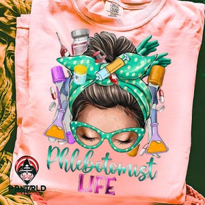 Może przedstawiać: Różowa koszulka Comfort Colors z grafiką kobiety w zielonej apaszce w kropki i okularach, otoczonej materiałami medycznymi. Tekst "Phlebotomist LIFE" jest wyświetlany poniżej.