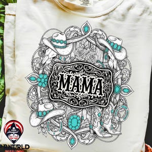 Op de afbeelding: Cr&egrave;mekleurig T-shirt met een gedetailleerde zwart-wit grafiek en turquoise accenten. Het ontwerp bevat cowboyhoeden, laarzen, een hoefijzer en het woord "MAMA" in een decoratief kader. Het shirt heeft een klassieke ronde hals.