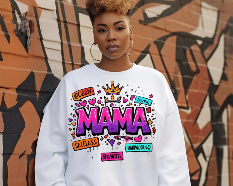May include: White sweatshirt with a colorful graphic design that says "MAMA" with words like "Queen", "Loving", "Selfless", "Hardworking", and "Beautiful" around it.
